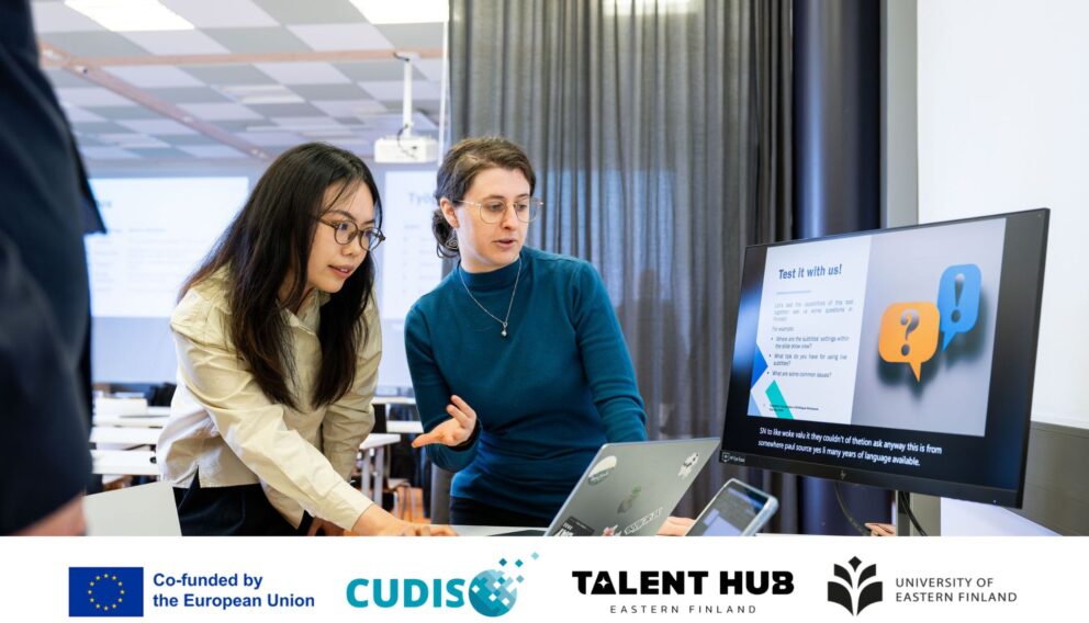 Two students standing by a computer hosting a tech demo station