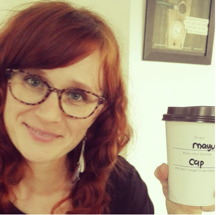 Kuvassa amanuenssi Maiju Parviainen hymyilee kahvikuppi kädessään.