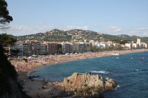 Landscape over a beach, city and a hill side by side.