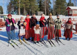 Joukko kansan- ja kansallispukuihin pukeutuneita hiihtäjiä