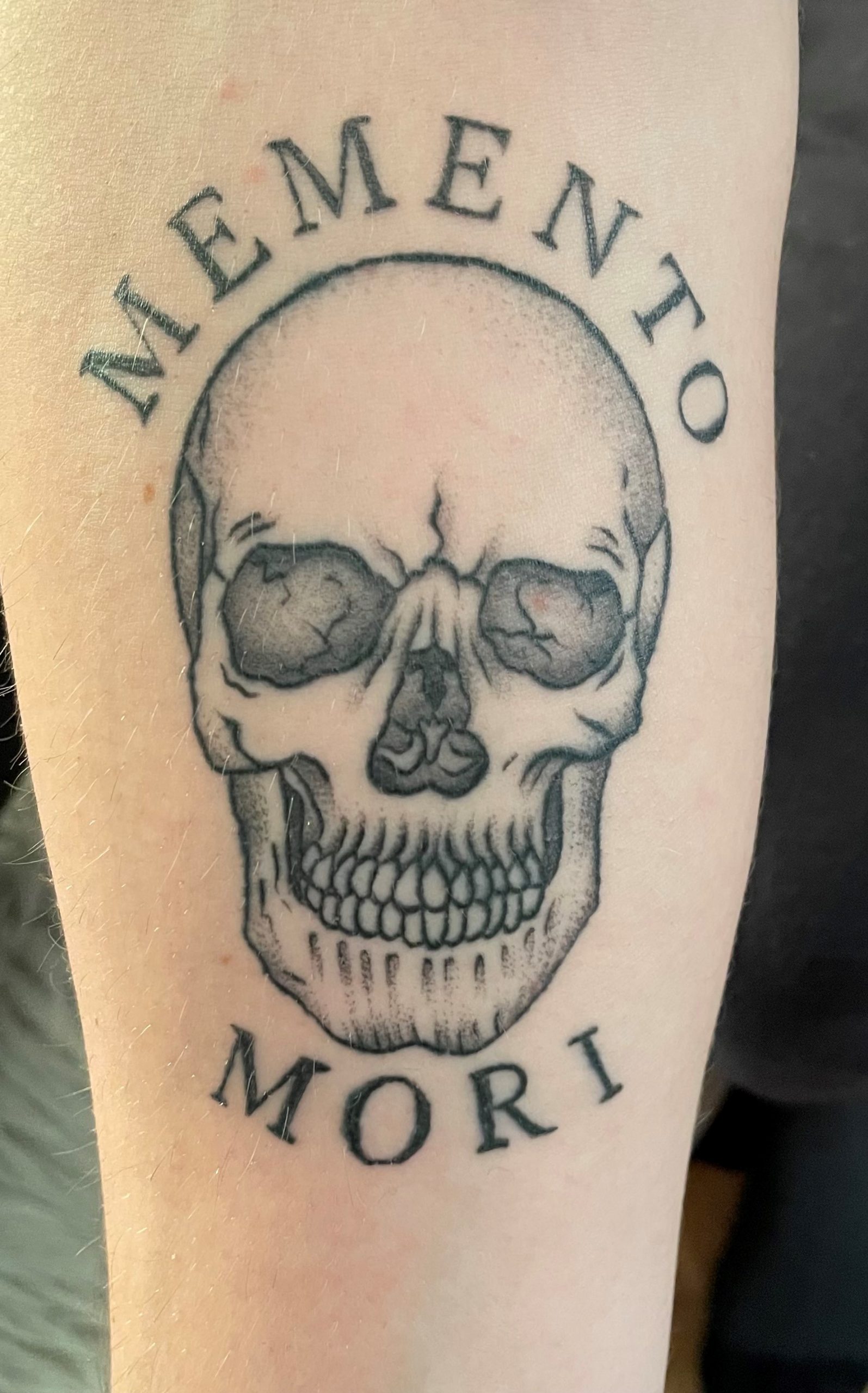 photo of a tattoo depicting a skull and a caption "memento mori"