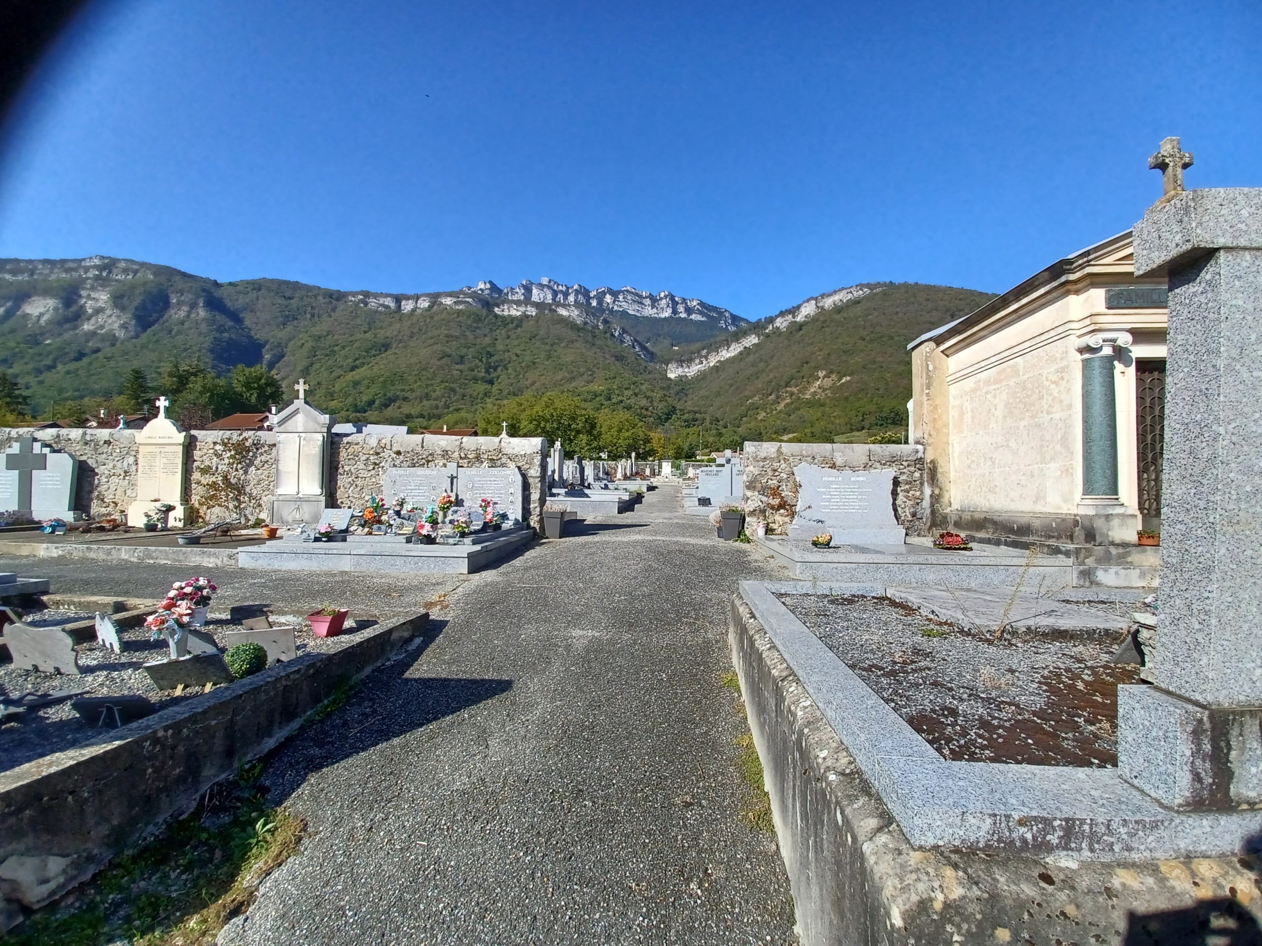 An alley at a French cemetary, with a view of the Alps