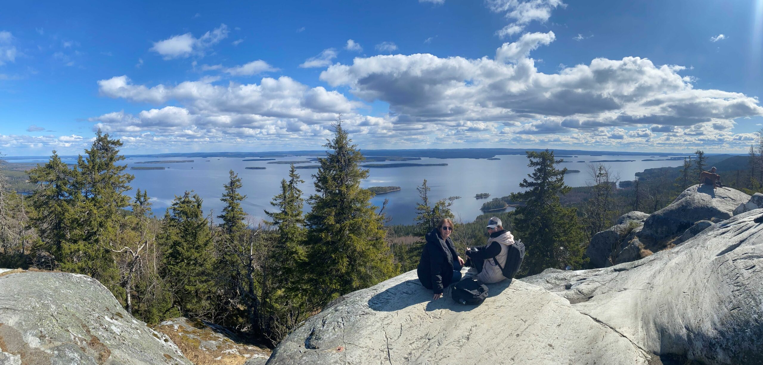 People sitting on a top of a hill with lake view.