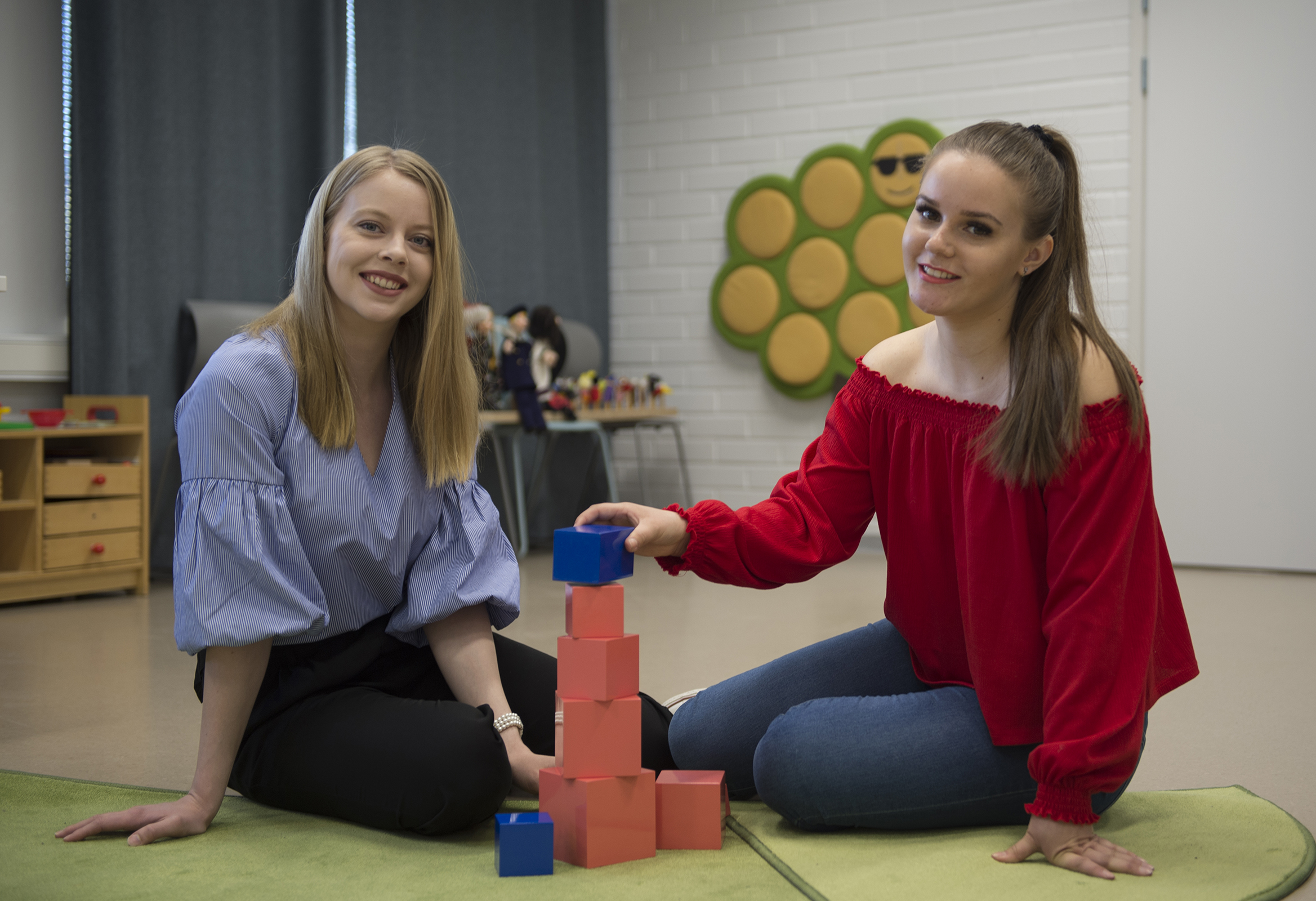 Kaksi varhaiskasvatuksen opettajaopiskelijaa istuvat rakentamassa pientä tornia palikoista.