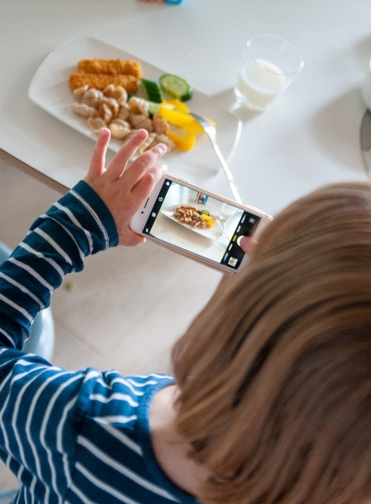 Lapsi ottaa puhelimella kuvaa ruoasta.