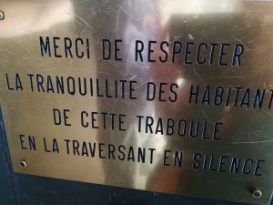 A sign that says Merci de respecter la tranquillite des habitant. De cette traboule en la traversant en silence.