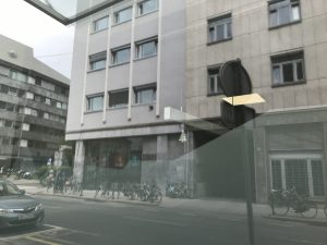 Streetview of National Radio building: grey concrete building, bikes and a car.