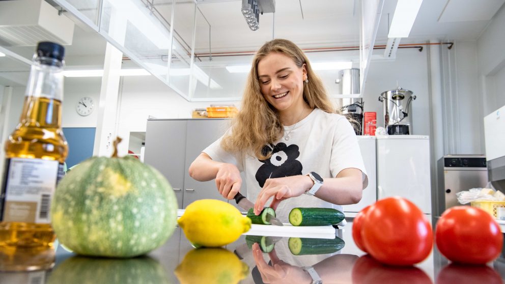 Ravitsemustieteen opiskelija pilkkomassa vihanneksia yliopiston opetuskeittiöllä