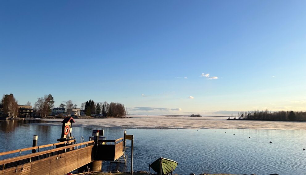 Järven rannalta otettu kuvituskuva, jossa jäät on alkaneet juuri sulaa.