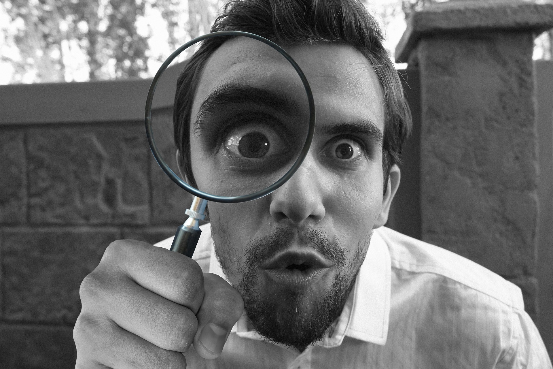 Mies katsoo suurennuslasin läpi. Man looks through a magnifying glass.