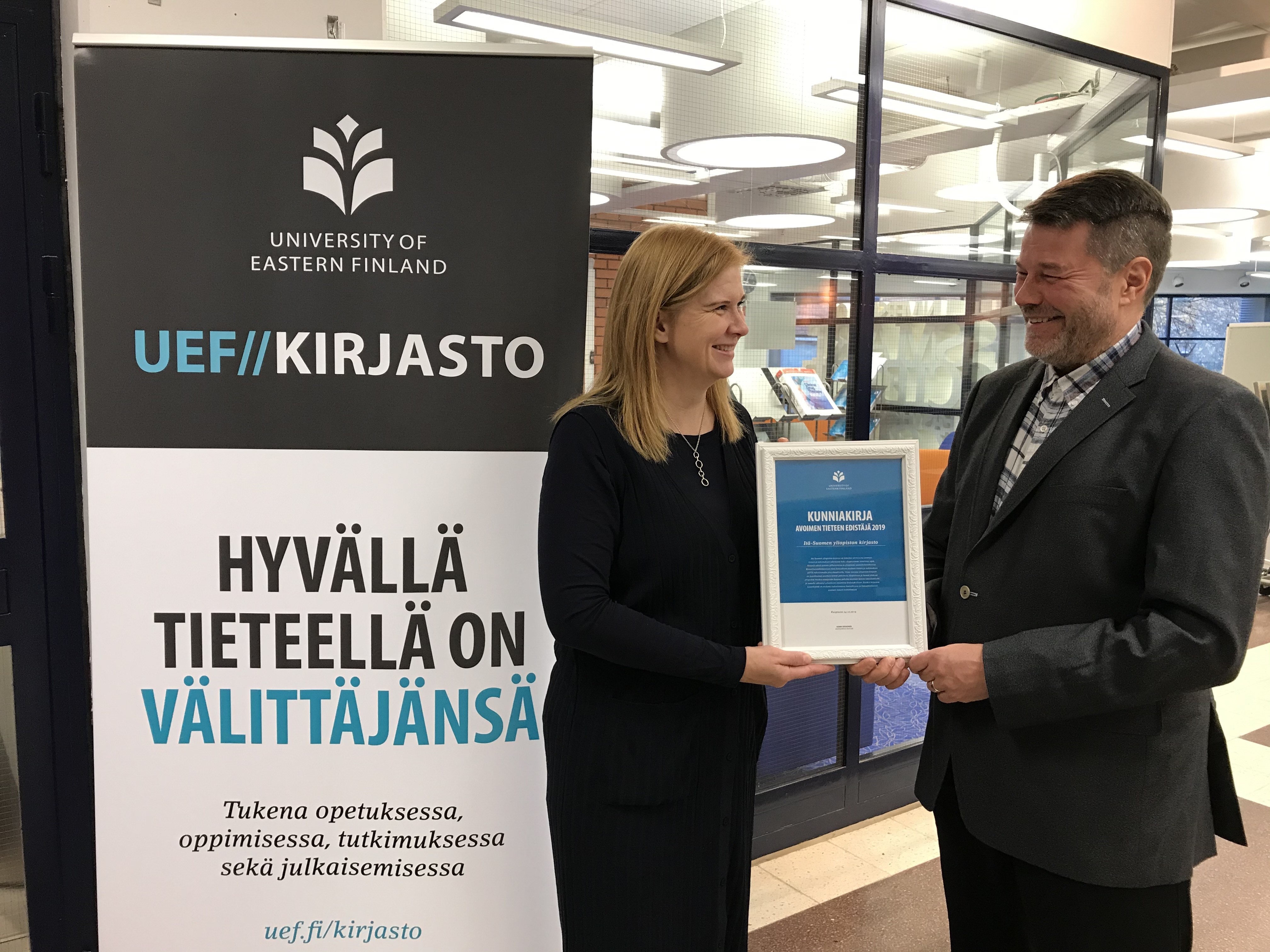 Kirjasto, rullajuliste, iloinen, nainen, mies, kunniakirja. Library, roll-up, happy, woman, man, award.