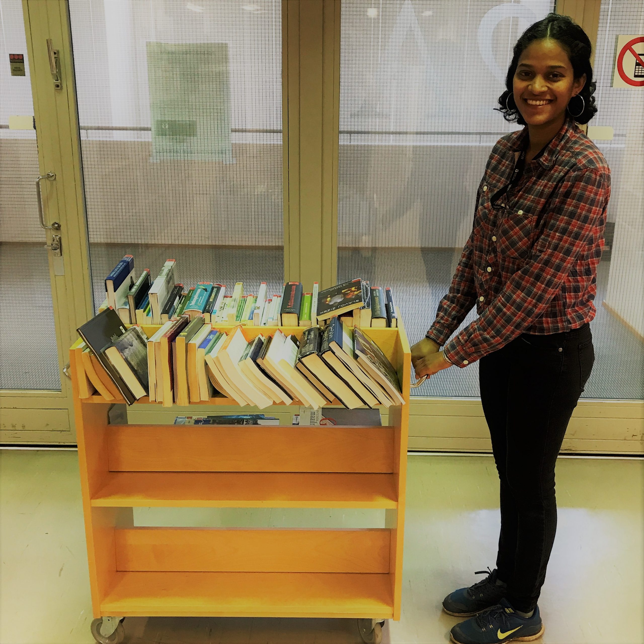 Kirjakärry jossa kirjoja, nuori nainen. Book trolley and a young woman.