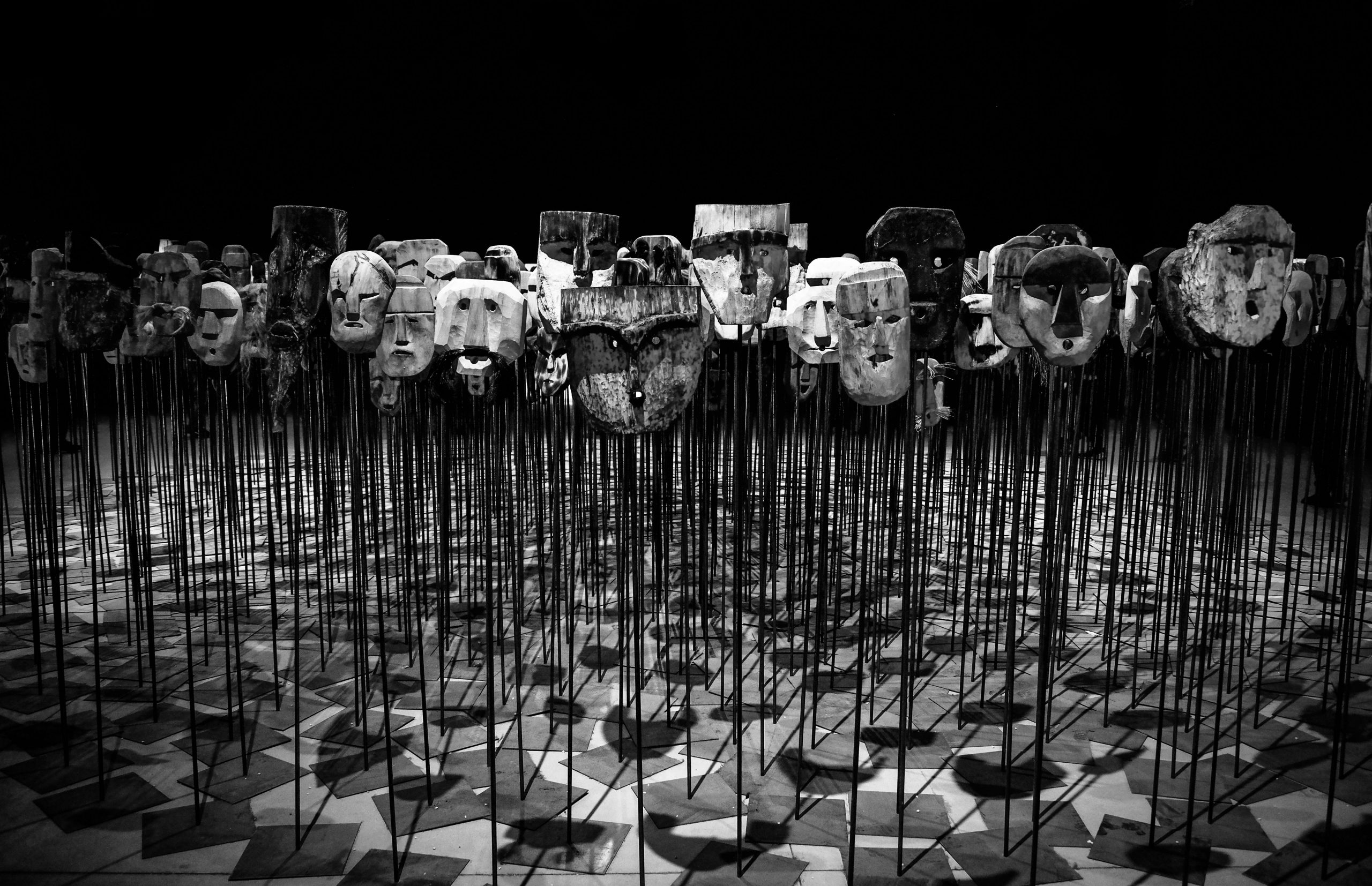 Harmaasävyvalokuva, jossa on keppien päälle asetettuja naamioita. | Grayscale photo of masks on a stick.