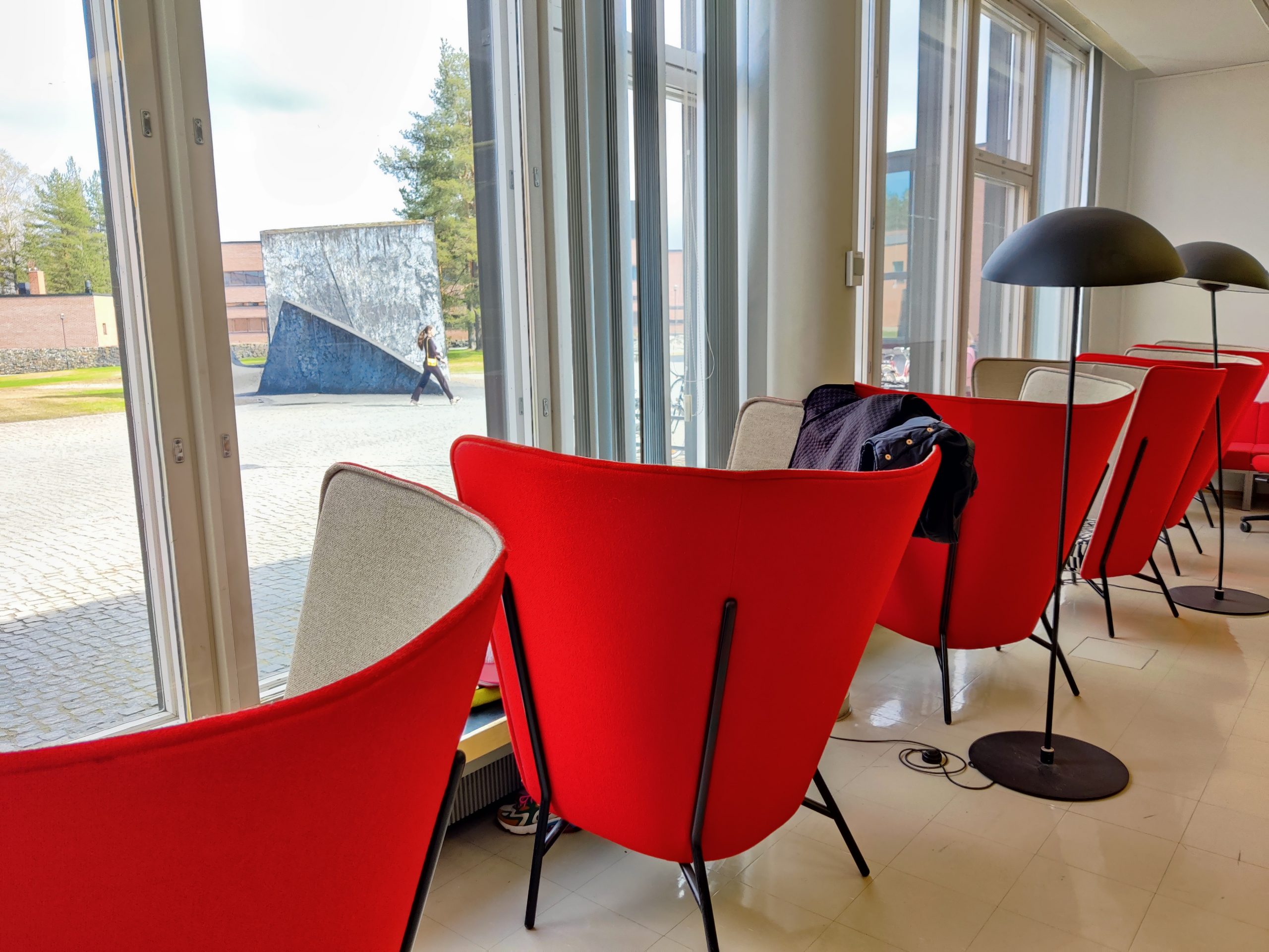 Nojatuoleja ja jalkalamppuja ikkunan luona Joensuun kampuskirjastossa. Comfy chairs and floor lamps close to the windows in Joensuu campus library.