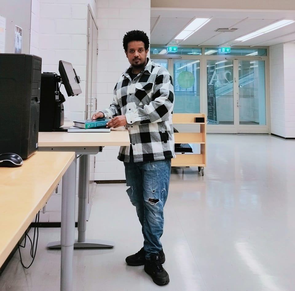 Michael Gebremedhin stands in front of a lending machine in hall 2A of Joensuu Campus Library.