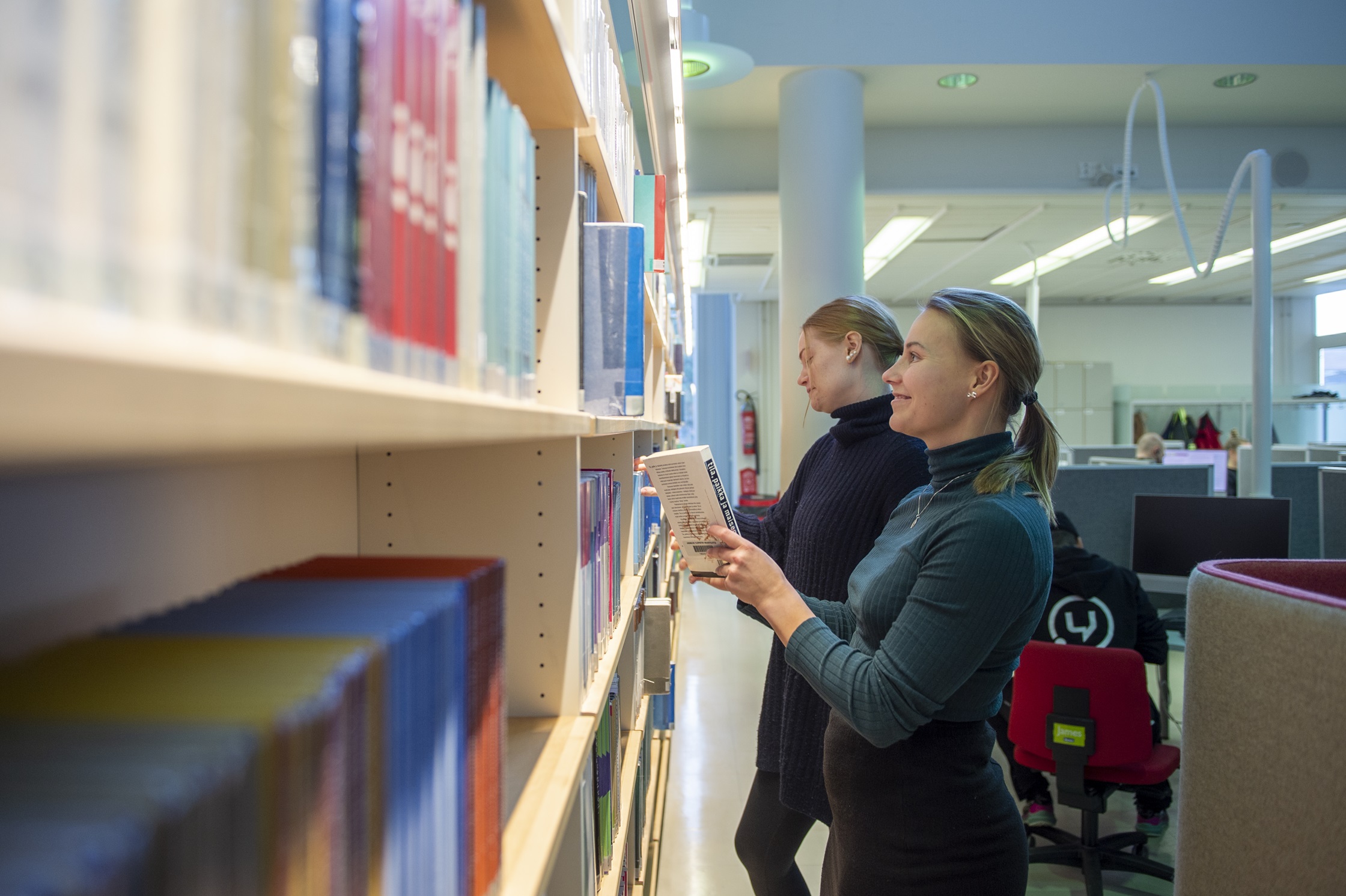 Kaksi opiskelijaa kirjahyllyn ääressä | Two students at a bookshelf