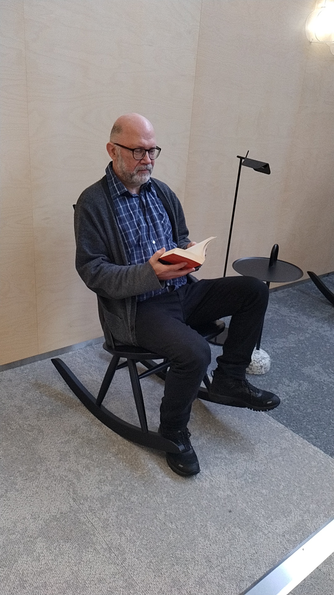 Mies lukee kirjaa keinutuolissa | A man reading a book in a rocking chair.