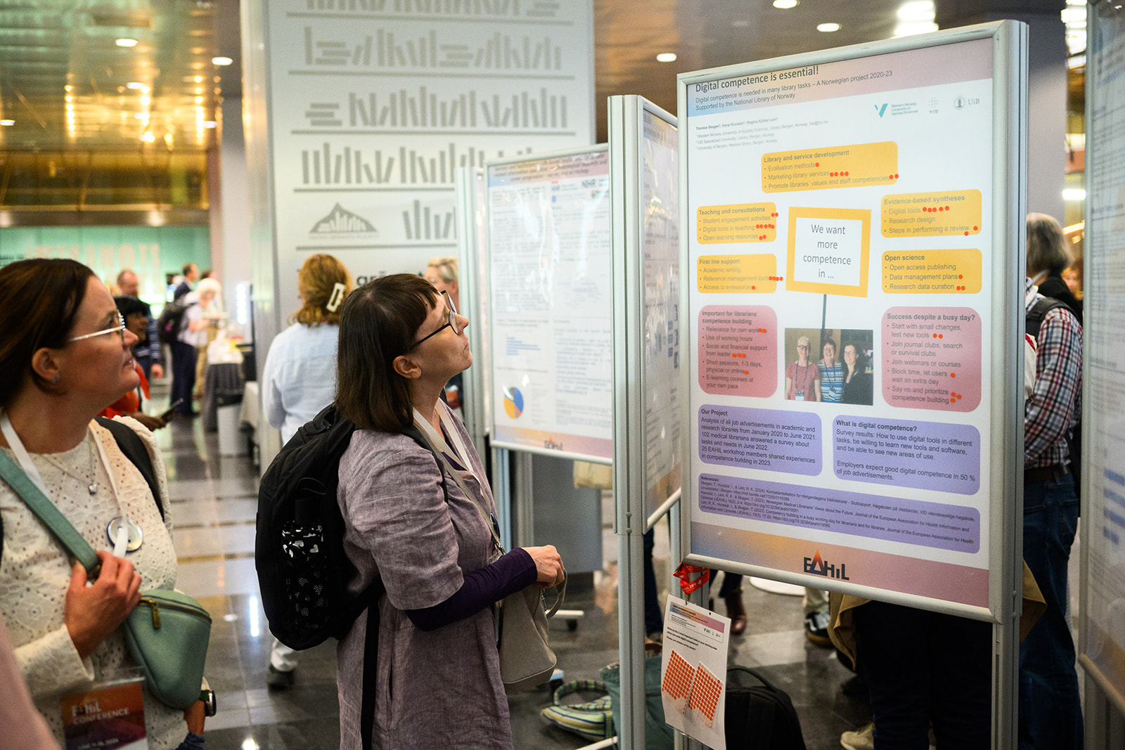 Ihmisiä katselemassa postereita konferenssissa. People looking at posters at the conference.