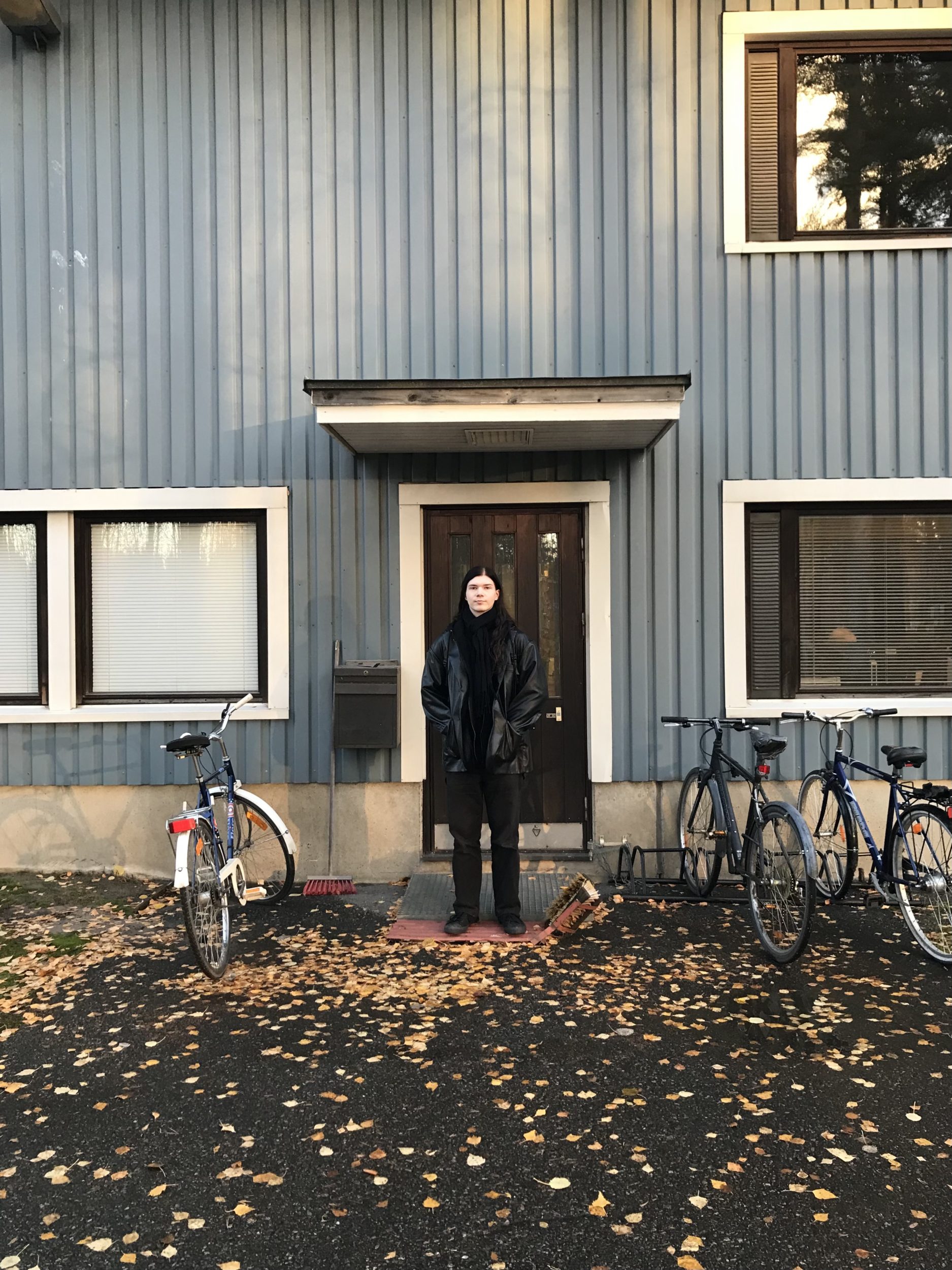 Mies seisoo oven edessä. | A man standing in front of a door.