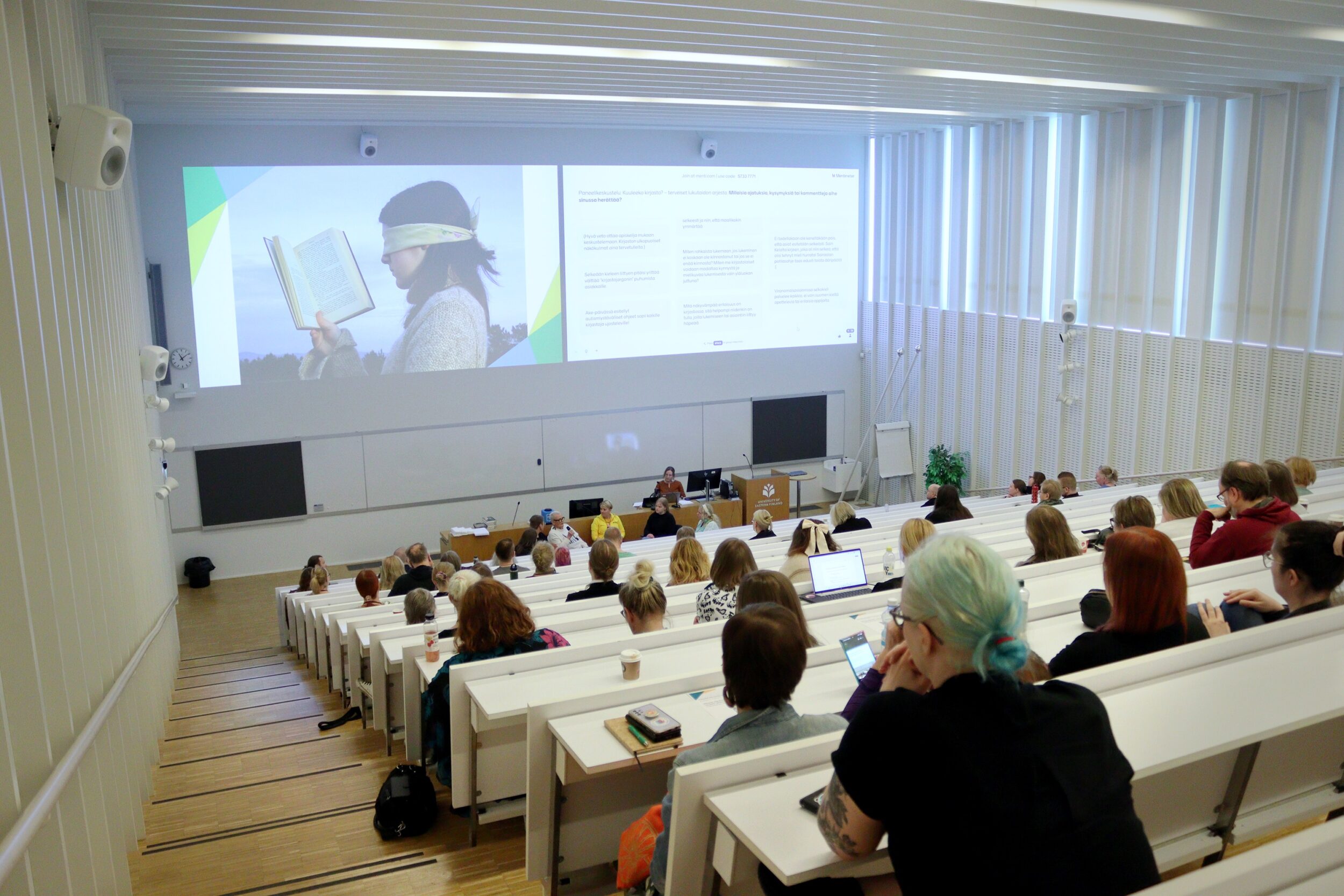 Itä-Suomen kirjastopäivien osallistujat seuraavat auditoriossa paneelikeskustelua. The guests of the Eastern Finland Library Days watch the panel discussion at the auditorium.