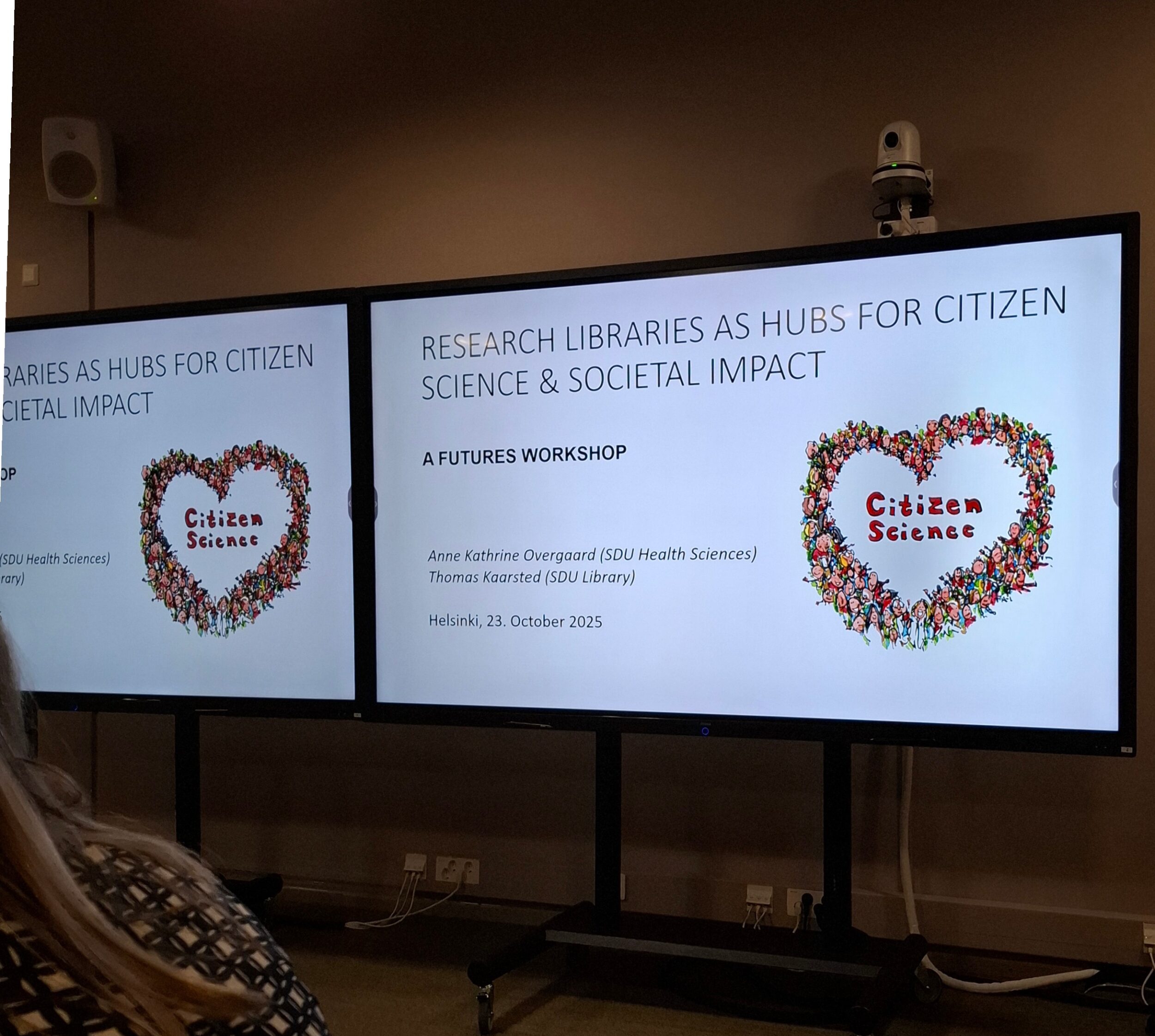 Torstain työpajan esitys näkyy kahdella näytöllä.Isolla teksti Research Libraries as Hubs for Citizen Science & Societal mpact.