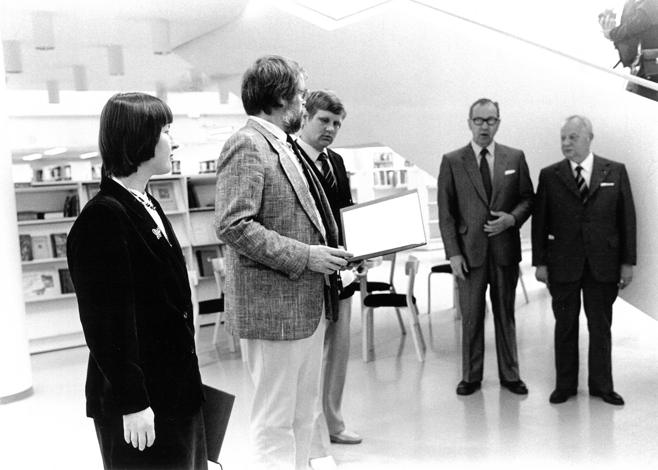 Viisi ihmistä seisomassa juhlallisessa tilaisuudessa.