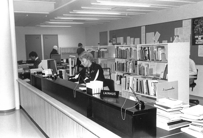 Library ciruclation desk with two staff members behind it.