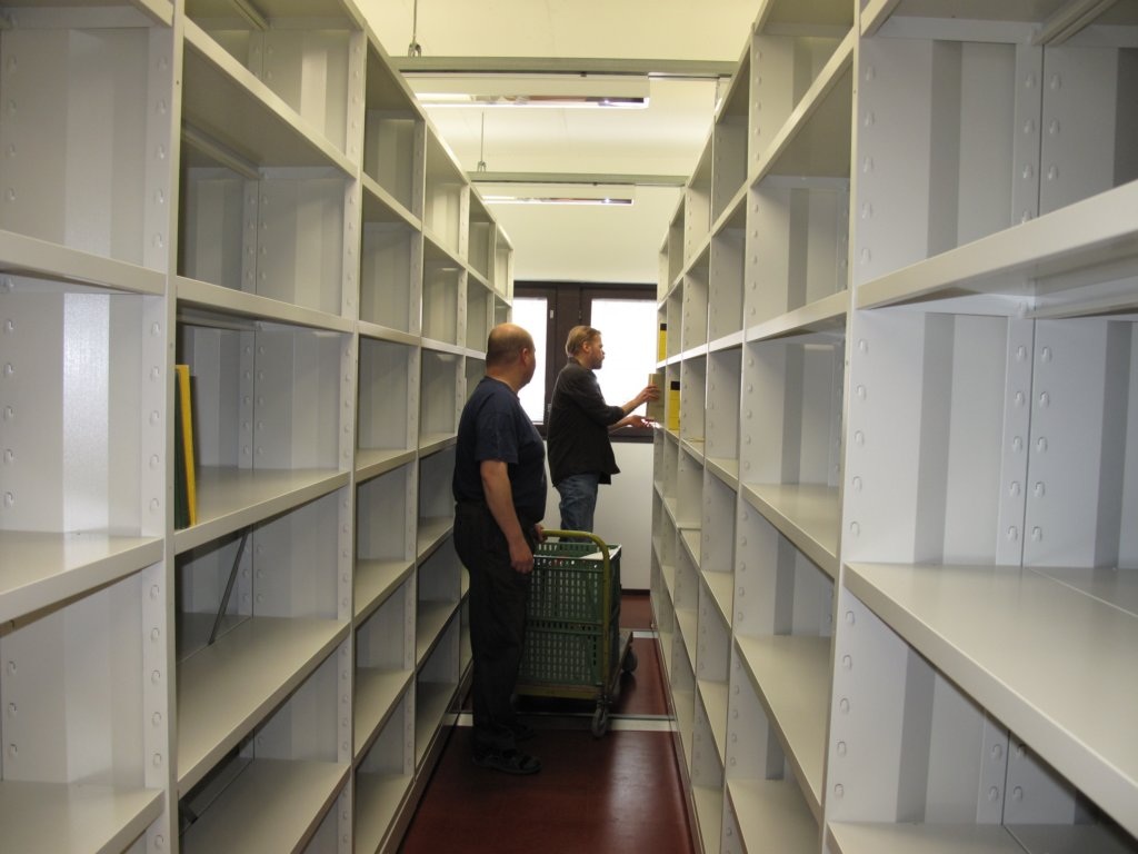 Kaksi miestä lähes tyhjien kirjahyllyjen välissä.