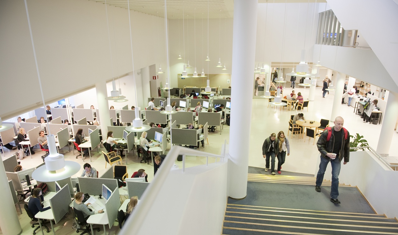Näkymä portailta alas laajaan saliin, jossa ihmisiä työskentelemässä tietokoneilla.
