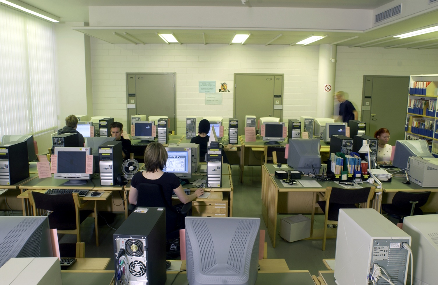 Nuoria ihmisiä istumassa tietokoneiden äärellä.