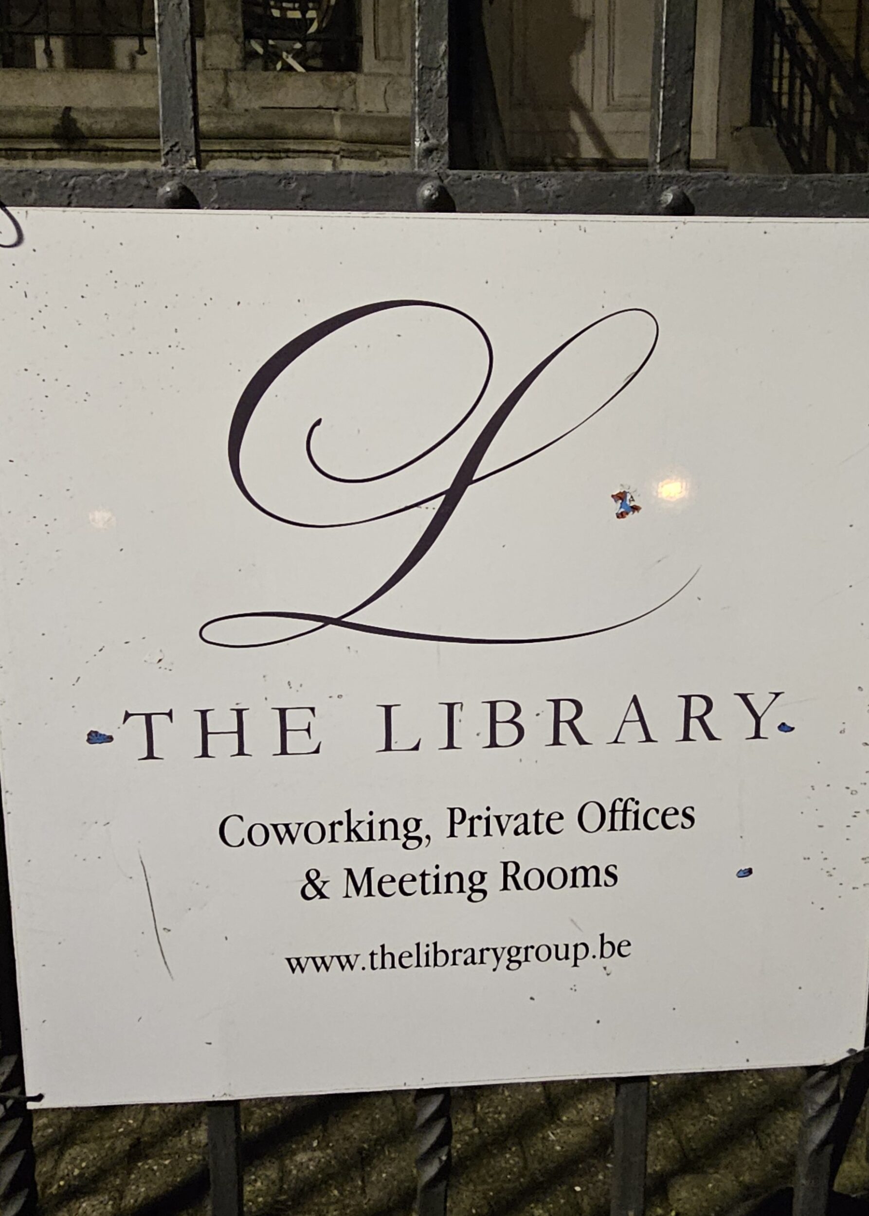 Kirjaston kyltti talon edessä. | A sign for the library in front of the building.